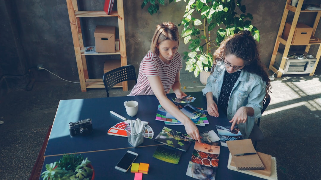 Two women discuss creative project with photos and swatches.